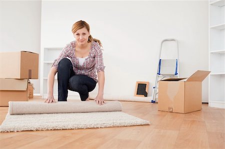 Pretty blonde woman rolling up a carpet to prepare to move house Stock Photo - Budget Royalty-Free & Subscription, Code: 400-04871243