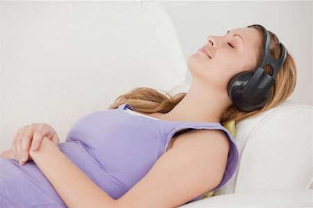 simsearch:400-04418452,k - Delighted blond-haired woman listening to music lying on the sofa in the living-room Photographie de stock - Aubaine LD & Abonnement, Code: 400-04871255