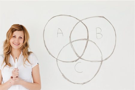 Smiling teacher looking at the camera while standing near a white board in a classroom Stock Photo - Budget Royalty-Free & Subscription, Code: 400-04871289