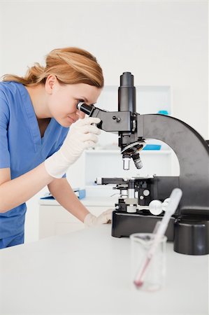 simsearch:400-05670345,k - Cute female scientist looking through a microscope in a lab Photographie de stock - Aubaine LD & Abonnement, Code: 400-04871333
