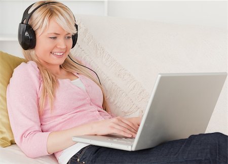 simsearch:400-04418454,k - Attractive female listening to music on her headphones while lying on a sofa in the living room Stockbilder - Microstock & Abonnement, Bildnummer: 400-04871475