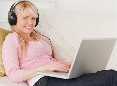 simsearch:400-04418454,k - Pretty woman listening to music on her headphones while lying on a sofa in the living room Stockbilder - Microstock & Abonnement, Bildnummer: 400-04871476