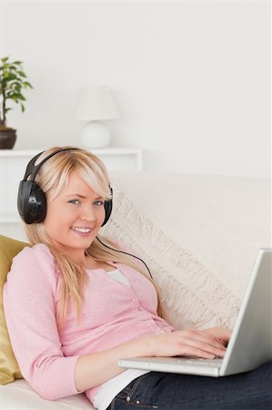 simsearch:400-04418454,k - Pretty female listening to music on her headphones while lying on a sofa in the living room Stockbilder - Microstock & Abonnement, Bildnummer: 400-04871477