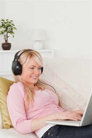 simsearch:400-04418454,k - Beautiful blonde woman listening to music on her headphones while lying on a sofa in the living room Foto de stock - Royalty-Free Super Valor e Assinatura, Número: 400-04871478
