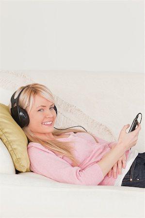 simsearch:400-04418454,k - Beautiful female listening to music on her headphones while lying on a sofa in the living room Foto de stock - Royalty-Free Super Valor e Assinatura, Número: 400-04871471