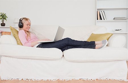 simsearch:400-04905827,k - Beautiful blonde female listening to music on her headphones while lying on a sofa in the living room Stock Photo - Budget Royalty-Free & Subscription, Code: 400-04871516