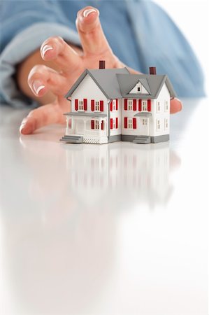 Womans Hand Reaching for Model House on a White Surface. Stock Photo - Budget Royalty-Free & Subscription, Code: 400-04871807