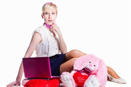 Portrait of beautiful blond girl wearing short skirt and white shoes near pink rabbit working with pink laptop on isolated white background Stockbilder - Microstock & Abonnement, Bildnummer: 400-04872514