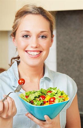 Pretty smiling young woman standing in the kitchen and holding a bowl with salad Stock Photo - Budget Royalty-Free & Subscription, Code: 400-04873458