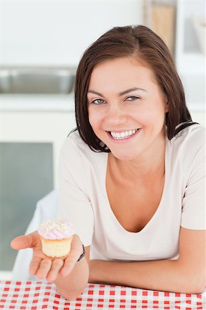 Laughing brunette showing a cupcake in her kitchen Stock Photo - Budget Royalty-Free & Subscription, Code: 400-04884072