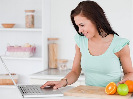 Young woman with a laptop and fruits in her kitchen Stock Photo - Budget Royalty-Free & Subscription, Code: 400-04884116