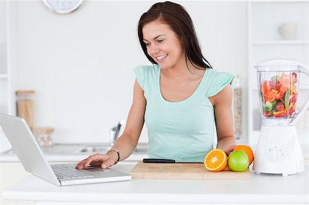 Young brunette with a laptop and fruits in her kitchen Stock Photo - Budget Royalty-Free & Subscription, Code: 400-04884117