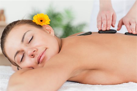 simsearch:400-04881818,k - Delighted woman having a hot stone massage with a flower on her ear Fotografie stock - Microstock e Abbonamento, Codice: 400-04884156
