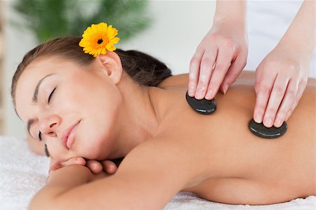 simsearch:400-04881818,k - Close up of a beautiful woman enjoying a hot stone massage with a flower on her ear Fotografie stock - Microstock e Abbonamento, Codice: 400-04884164