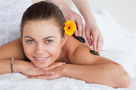 simsearch:400-04881816,k - Smiling woman enjoying a hot stone massage with a flower on her ear Stockbilder - Microstock & Abonnement, Bildnummer: 400-04884166