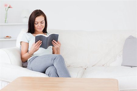 Smiling dark-haired woman reading a book in her living room Stock Photo - Budget Royalty-Free & Subscription, Code: 400-04884215