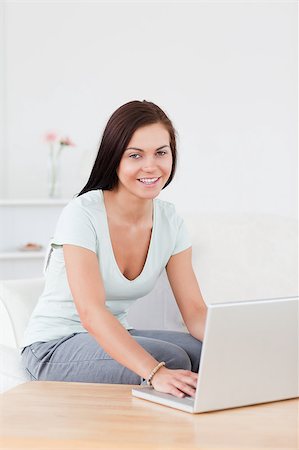 Portrait of a young woman typing on her laptop in her living room Stock Photo - Budget Royalty-Free & Subscription, Code: 400-04884233