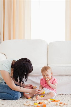 Beautiful woman playing with her baby in while sitting on a carpet in the living room Foto de stock - Super Valor sin royalties y Suscripción, Código: 400-04884520