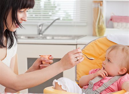 Beautiful brunette woman feeding her baby while sitting in the kitchen Stock Photo - Budget Royalty-Free & Subscription, Code: 400-04884534