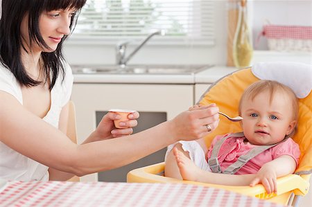 Attractive brunette woman feeding her baby while sitting in the kitchen Stock Photo - Budget Royalty-Free & Subscription, Code: 400-04884531