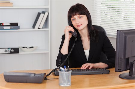 simsearch:400-04894274,k - Pretty brunette woman on the phone  while working on a computer in the office Stock Photo - Budget Royalty-Free & Subscription, Code: 400-04884577