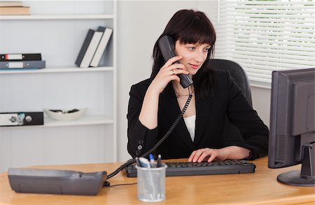 simsearch:400-04894274,k - Attractive brunette woman on the phone while working on a computer in the office Stock Photo - Budget Royalty-Free & Subscription, Code: 400-04884578
