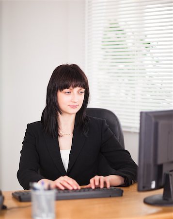 simsearch:400-04894274,k - Attractive brunette woman working on a computer while sitting at a desk in the office Stock Photo - Budget Royalty-Free & Subscription, Code: 400-04884573