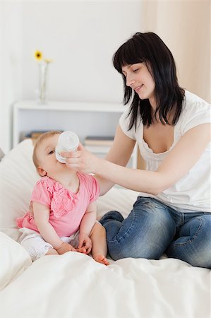 Pretty brunette female bottle-feeding her baby on a bed in her appartment Stock Photo - Budget Royalty-Free & Subscription, Code: 400-04884634