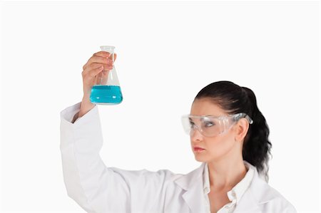 Dark-haired scientist conducting an experiment while looking at a blue flask Stock Photo - Budget Royalty-Free & Subscription, Code: 400-04886347