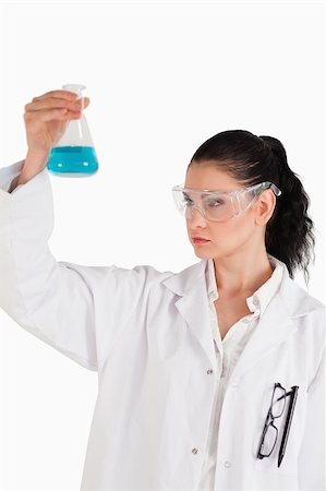 Dark-haired woman conducting an experiment while looking at a blue flask Stock Photo - Budget Royalty-Free & Subscription, Code: 400-04886348