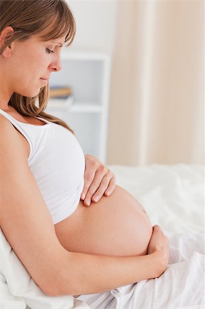 Portrait of a charming pregnant female lying on a bed in her apartment Stock Photo - Budget Royalty-Free & Subscription, Code: 400-04886461