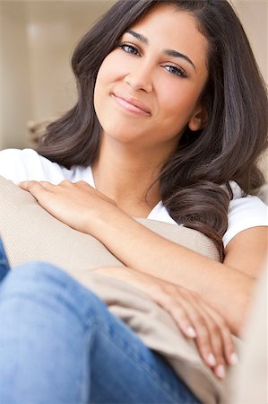 simsearch:400-05733700,k - Portrait of a beautiful young Latina Hispanic woman or girl sitting at home on a sofa holding a cushion smiling and happy Photographie de stock - Aubaine LD & Abonnement, Code: 400-04880616