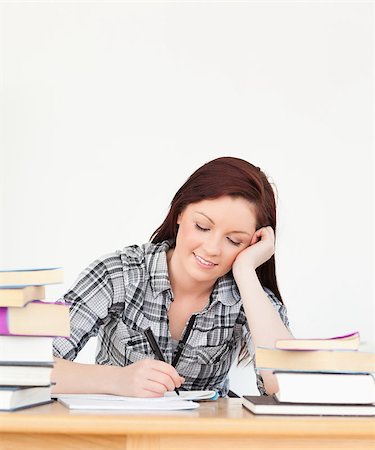 simsearch:400-04829236,k - Attractive happy red-haired girl studying for an examination at her desk Stock Photo - Budget Royalty-Free & Subscription, Code: 400-04880845