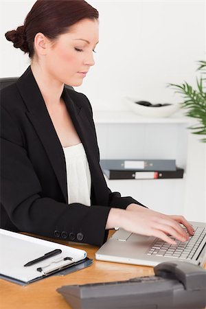 simsearch:400-04894274,k - Young attractive red-haired woman in suit typing on her laptop while sitting in an office Stock Photo - Budget Royalty-Free & Subscription, Code: 400-04881054