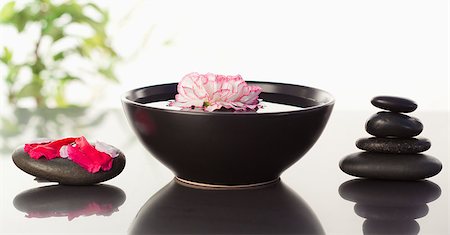 simsearch:400-04640528,k - Pink carnation floating in a bowl with petals on a black stone on one side and a stack ok black stones on the other side Stock Photo - Budget Royalty-Free & Subscription, Code: 400-04881239