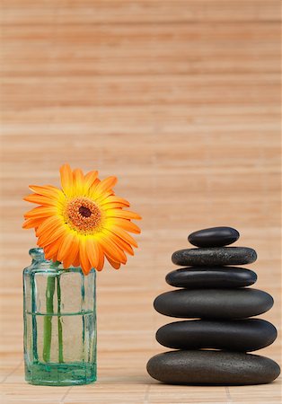 Orange snflower in a glass flask beside a black stones stack against a bamboo background Stock Photo - Budget Royalty-Free & Subscription, Code: 400-04881308
