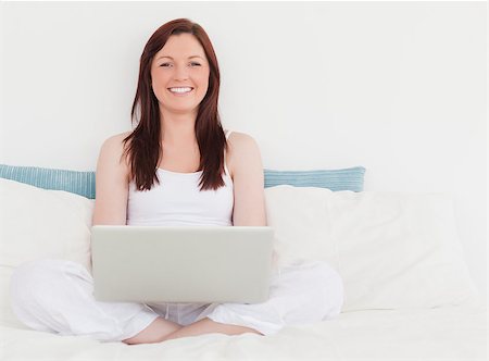 simsearch:400-04881612,k - Pretty red-haired female relaxing with her laptop while sitting on her bed Stock Photo - Budget Royalty-Free & Subscription, Code: 400-04881498