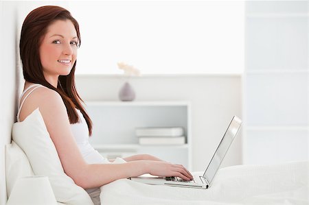 Beautiful red-haired female relaxing with her laptop while sitting on her bed Stock Photo - Budget Royalty-Free & Subscription, Code: 400-04881491