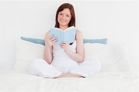 simsearch:400-04881612,k - Gorgeous red-haired woman reading a book while sitting on her bed Stock Photo - Budget Royalty-Free & Subscription, Code: 400-04881507