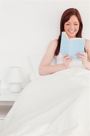 simsearch:400-05894862,k - Pretty red-haired female reading a book while sitting on her bed Foto de stock - Super Valor sin royalties y Suscripción, Código: 400-04881605