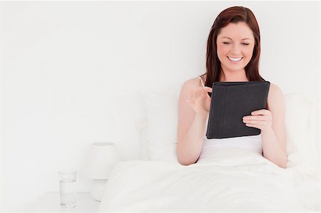simsearch:400-05894862,k - Beautiful red-haired woman relaxing with her tablet while sitting on her bed Foto de stock - Super Valor sin royalties y Suscripción, Código: 400-04881614