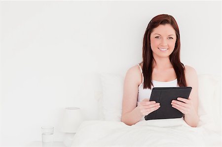 simsearch:400-05894862,k - Good looking red-haired woman relaxing with her tablet while sitting on her bed Foto de stock - Super Valor sin royalties y Suscripción, Código: 400-04881615