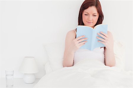 simsearch:400-05894862,k - Attractive red-haired woman reading a book while sitting on her bed Foto de stock - Super Valor sin royalties y Suscripción, Código: 400-04881612