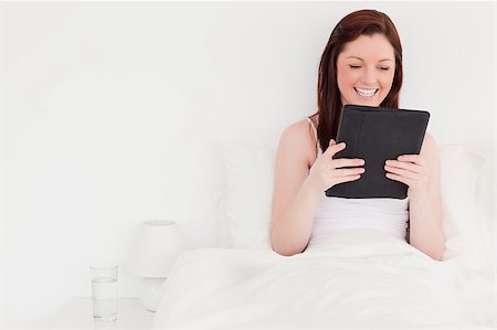 simsearch:400-05894862,k - Attractive red-haired woman relaxing with her tablet while sitting on her bed Foto de stock - Super Valor sin royalties y Suscripción, Código: 400-04881613