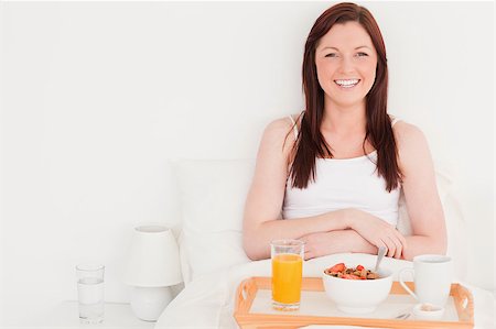 simsearch:400-04881612,k - Beautiful red-haired woman having her breakfast while sitting on her bed Stock Photo - Budget Royalty-Free & Subscription, Code: 400-04881626