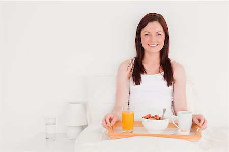 simsearch:400-04881612,k - Attractive red-haired woman having her breakfast while sitting on her bed Stock Photo - Budget Royalty-Free & Subscription, Code: 400-04881627