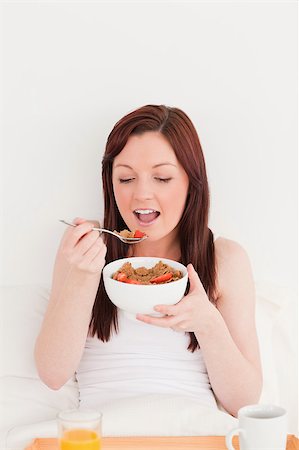 simsearch:400-04881612,k - Good looking red-haired female having her breakfast while sitting on her bed Stock Photo - Budget Royalty-Free & Subscription, Code: 400-04881637