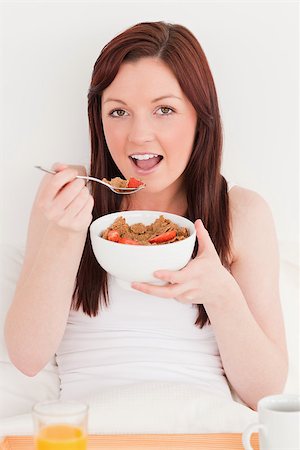 simsearch:400-04881612,k - Cute red-haired female having her breakfast while sitting on her bed Stock Photo - Budget Royalty-Free & Subscription, Code: 400-04881638