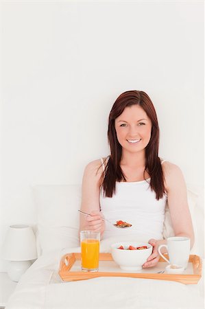 simsearch:400-04881612,k - Good looking red-haired woman having her breakfast while sitting on her bed Stock Photo - Budget Royalty-Free & Subscription, Code: 400-04881630