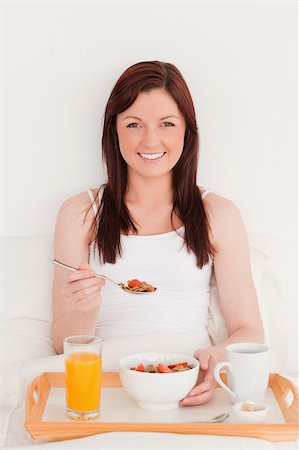 simsearch:400-04881612,k - Gorgeous red-haired woman having her breakfast while sitting on her bed Stock Photo - Budget Royalty-Free & Subscription, Code: 400-04881632